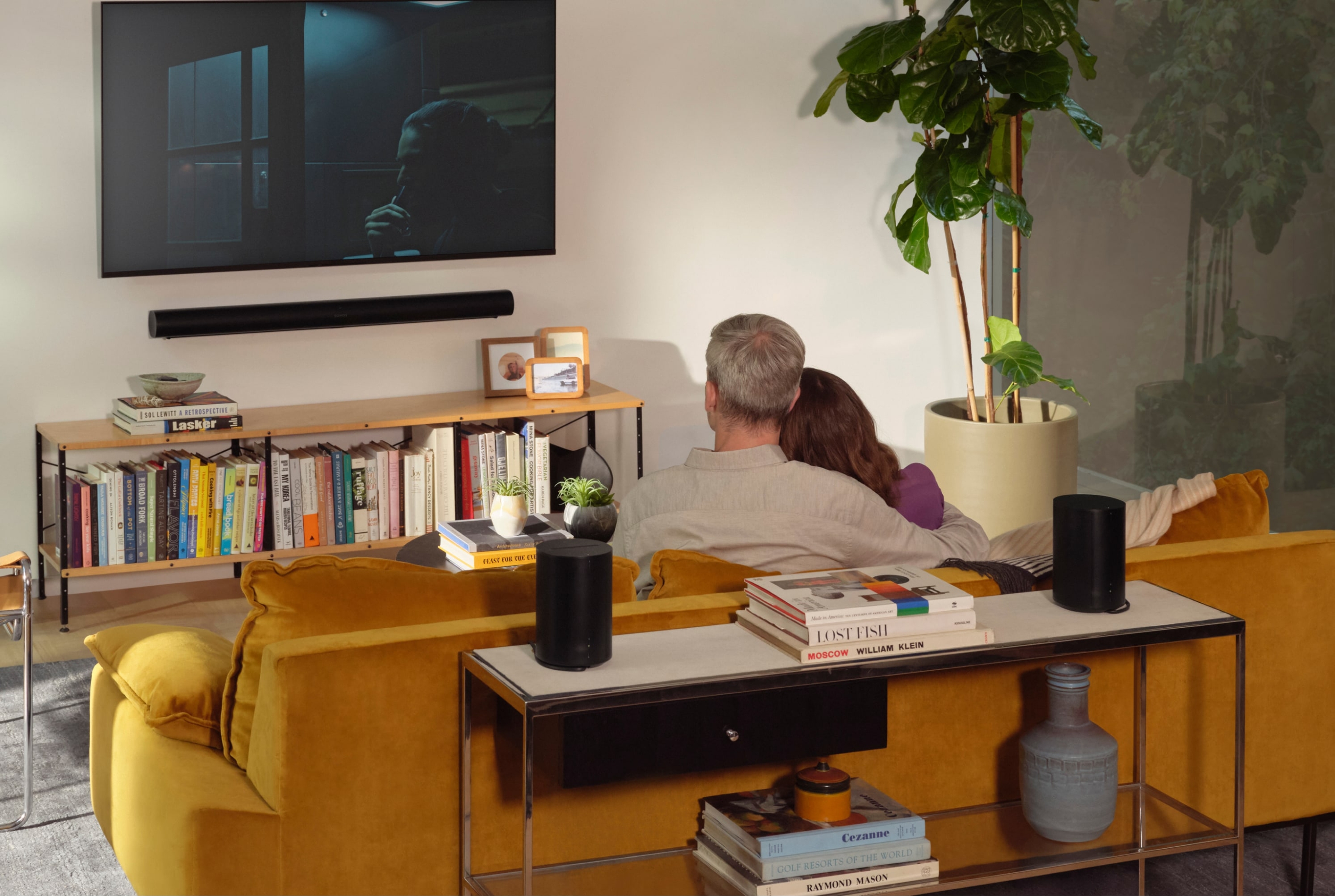 Paar mit einem Surround Set aus Sonos Arc und Era 100 in einem Wohnzimmer.