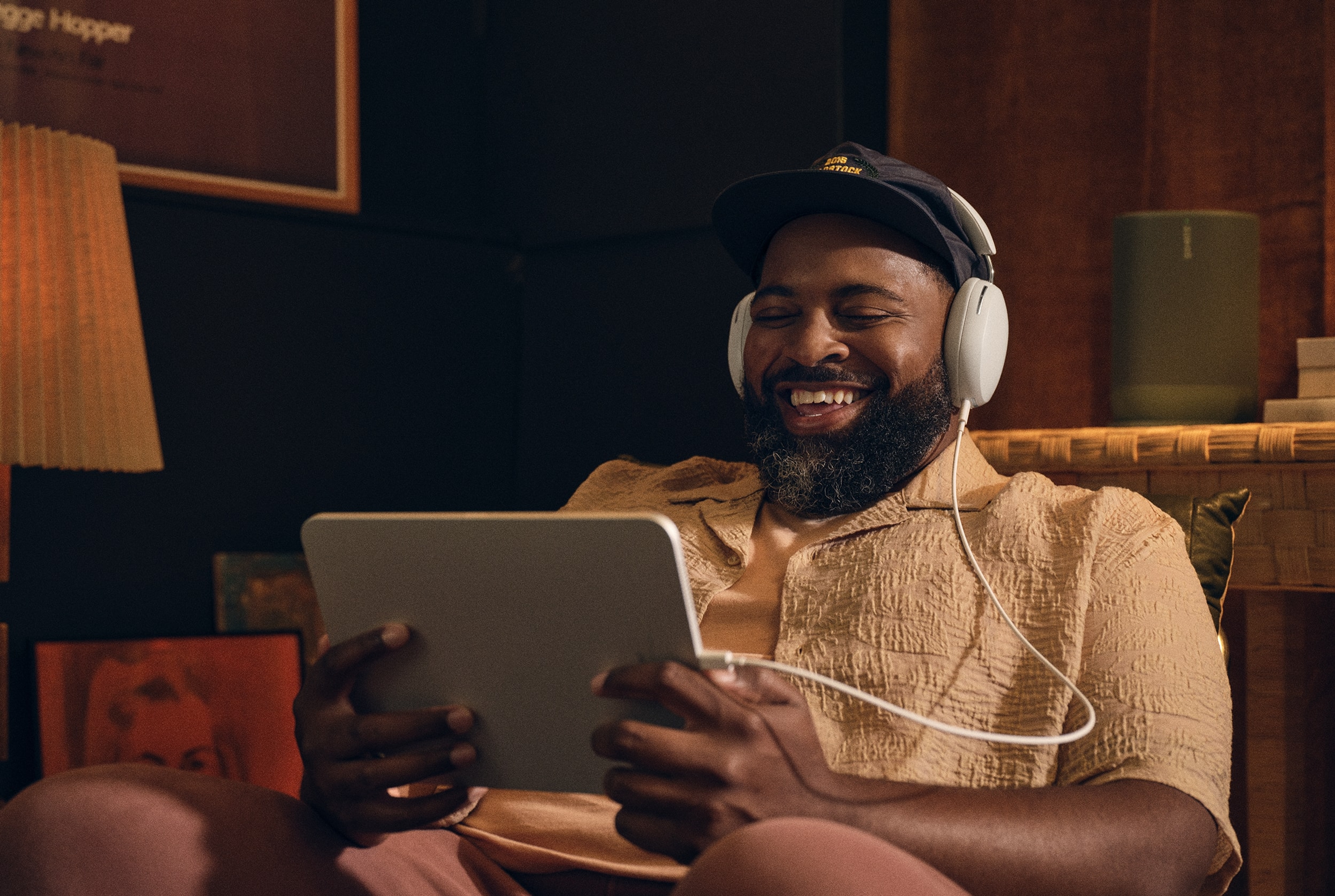 Person sitting in living room listening to white Sonos Ace headphones