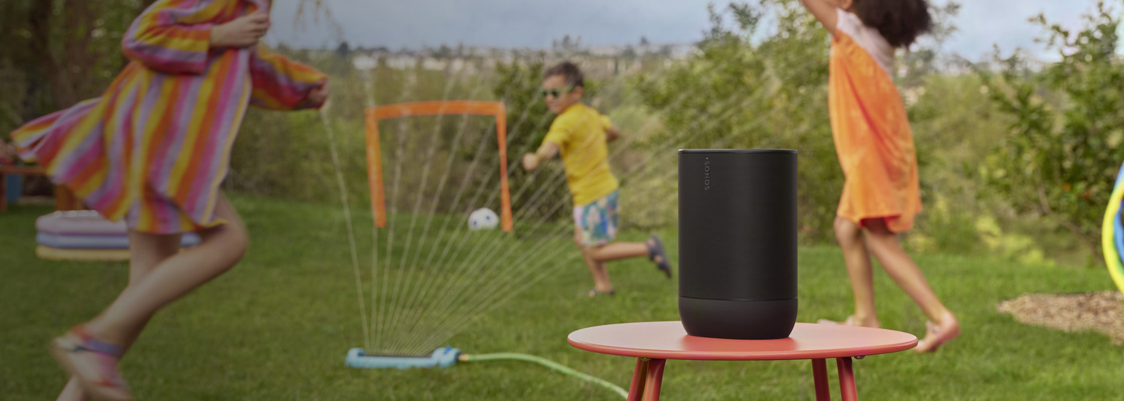 Sonos Move 2 na stojaku i dzieci bawiące się na zewnątrz