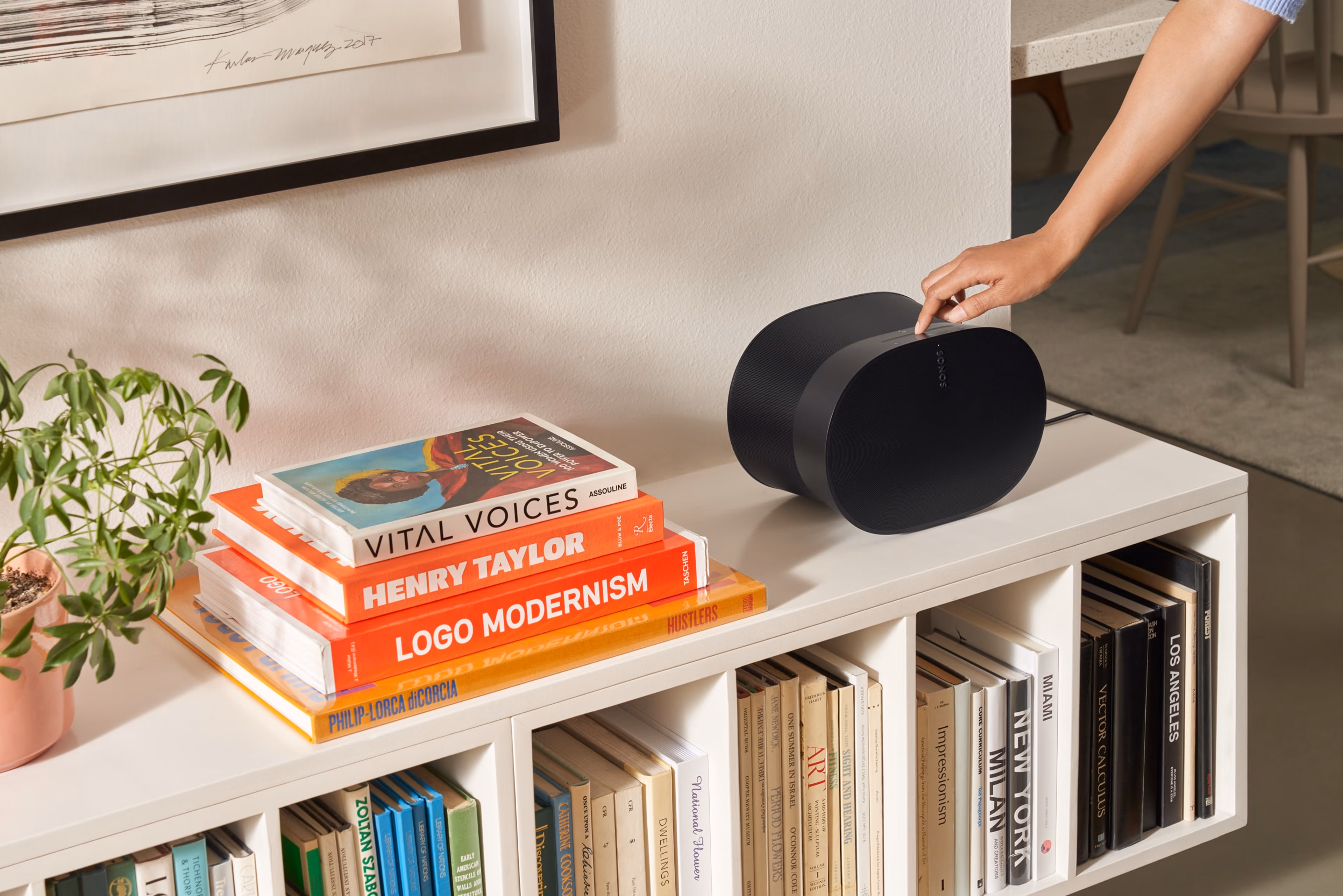 Woman using the touch controls of a black Era 300 on a bookshelf